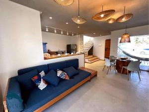 a living room with a blue couch and a dining room at Casa a 1200m da Praia do Patacho - Casa Garaguá in Pôrto de Pedras +37 photos