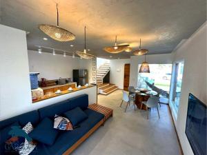 a living room with a blue couch and a kitchen at Casa a 1200m da Praia do Patacho - Casa Garaguá in Pôrto de Pedras