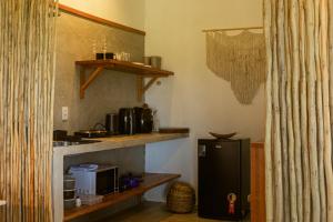 a kitchen with a small black refrigerator and shelves at Vila das Pedras in Caraíva