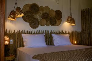 a bedroom with a bed with hats on the wall at Vila das Pedras in Caraíva