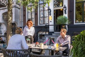 a group of people sitting at a table in a patio at Mister Highland Hotel in Amsterdam