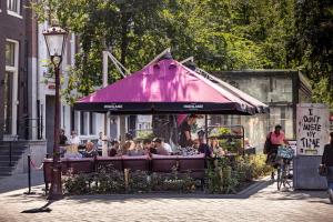 a group of people sitting at a restaurant under a purple umbrella at Mister Highland Hotel in Amsterdam