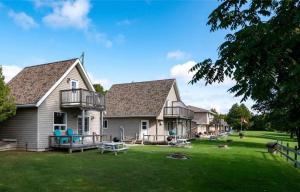 une grande maison avec une grande cour avec des tables et des chaises dans l'établissement Lions Head Beach Motel & Cottages - WATERFRONT, à Lion's Head