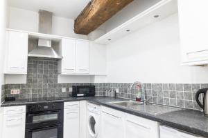 une cuisine avec des armoires blanches et un évier dans l'établissement Leeds City Centre New Apartment, à Leeds