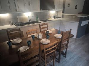 a kitchen with a wooden table and chairs with plates and bowls at Maison entière privée in Charleroi