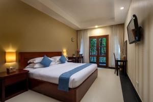 a bedroom with a bed with a television and a table at Skyline Boutique Hotel in Phnom Penh
