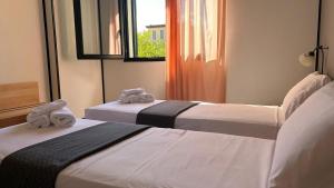 zwei Betten in einem Hotelzimmer mit Handtüchern darauf in der Unterkunft GRAN DELTA River & Nature Hotel in Rosolina