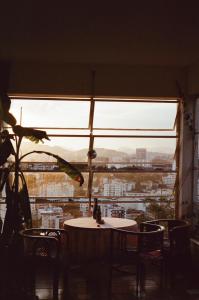 里约热内卢Quarto com varanda no paraíso的有窗户的房间里有一张桌子和几把椅子