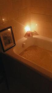 里约热内卢Quarto com varanda no paraíso的浴室里有浴缸，浴缸旁挂着一幅画，还有一根蜡烛。