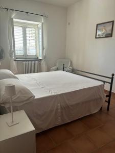 a bedroom with a large white bed and a window at Casa Vacanze Primavera in Maratea