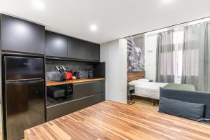 a kitchen with black cabinets and a table and a bedroom at VR OBREGON APARTMENTS in Madrid +65 photos