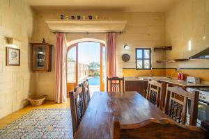 cocina con mesa de madera y ventana grande en Holiday Farmhouse with Private Pool, en Taʼ Gorgun