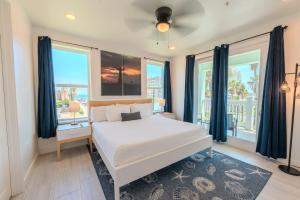 a bedroom with a white bed and two windows at Marisol Condo 301 in South Padre Island +33 photos