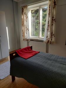 a bedroom with a bed with a red pillow and a window at Majoitus jaetuissa huoneissa sisältäen ruokailut in Lappeenranta