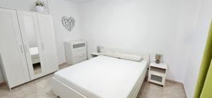 a white bedroom with a bed and a mirror at Escapada al Sur in Morro del Jable