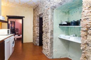Una cocina con una pared de piedra con estantes. en Apartaments Can Gibert, en Castelló d'Empúries