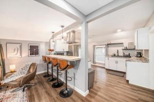 a kitchen with white cabinets and a bar with stools at Cityscape Suite - New Corporate Apt Downtown in Grand Rapids