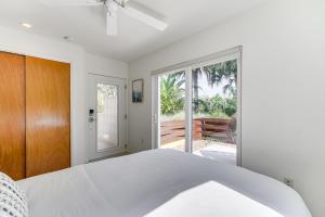 メルボルン・ビーチにあるPrivate Oasis with Pool Walk to Melbourne Beach!の白いベッドルーム(ベッド1台付)、ガラスのスライドドアが備わります。 +24枚の写真