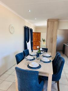 a wooden table with chairs and plates and wine glasses at 02 in Bel Aire place in Kempton Park