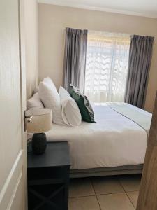 a bedroom with a bed with pillows and a window at 02 in Bel Aire place in Kempton Park