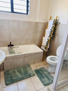 a bathroom with a tub and a toilet and two rugs at 02 in Bel Aire place in Kempton Park