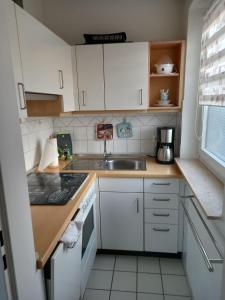 a small kitchen with white cabinets and a sink at Ferienwohnung Möwenschiss - Haus Bake in Büsum