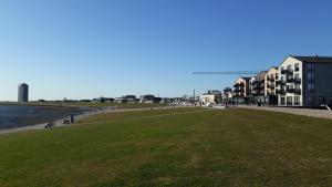 a view of a beach with buildings and grass at Ferienwohnung Möwenschiss - Haus Bake in Büsum