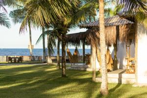a house on the beach with palm trees and a hammock at Vila das Pedras in Caraíva +6 photos
