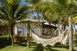 a hammock in front of a resort with palm trees at Vila das Pedras in Caraíva