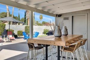 a wooden table with chairs and vases on a patio at Nova Gypsy Vanner by PaseoHomesAZ with Pool & Pool in Phoenix