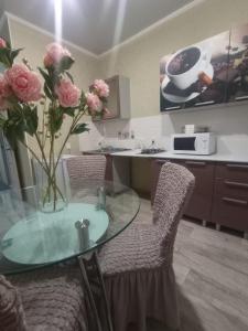 a kitchen with a glass table and chairs with flowers at VIP 5 Квартира 2ком in Oral +5 photos