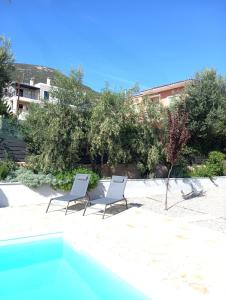 two white chairs sitting on the sand near a swimming pool at Villa Artia in Xiropigado
