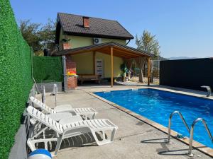 a swimming pool with white chairs and a house at Rest House in Slavinovići