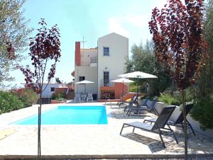 a swimming pool with chairs and umbrellas next to a building at Villa Artia in Xiropigado