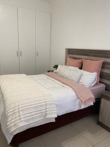Un dormitorio con una cama grande con almohadas blancas y rosas. en Windhoek Holiday Apartment, en Windhoek