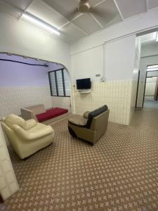 ジョージタウンにあるCJA Homestay Jalan Perakの椅子2脚、ソファ、テレビが備わる客室です。