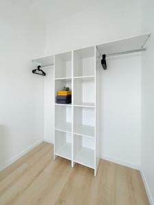 a white book shelf in a room with white walls at Principia Conciergerie - Le Petit nid cosy Corbeil in Corbeil-Essonnes