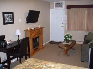Sala de estar con cama, escritorio y TV en Travellers Motel, en Cranbrook