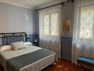 a bedroom with a bed and two windows at Finca Paraíso Rural in El Burgo de Osma
