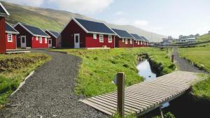 eine Reihe roter Häuser mit einem Fluss davor in der Unterkunft Discover This Well-appointed Cottage H in Vágur