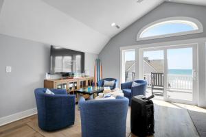 a living room with chairs and a table with a view of the ocean at Grand Topsail Villa by Sea Scape Properties in North Topsail Beach