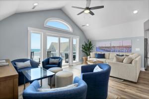 a living room with blue chairs and a couch at Grand Topsail Villa by Sea Scape Properties in North Topsail Beach