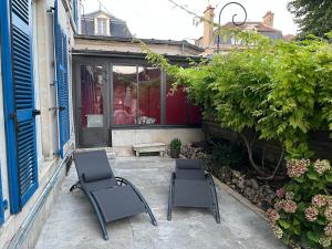 two chairs sitting on a patio in front of a house at La Maison Majorelle in Bar-sur-Aube