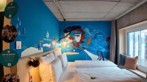 a bedroom with a blue wall with a mural at Villa Viva - ein Haus das Brunnen baut in Hamburg