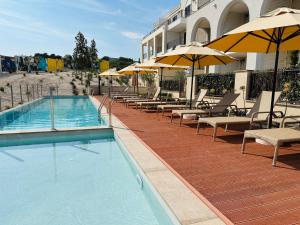a swimming pool with chairs and umbrellas next to a building at Apartments SLAVA in Radovici