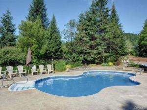 een zwembad met ligstoelen en een parasol bij Condo cottage-style Tremblant in Saint-Jovite