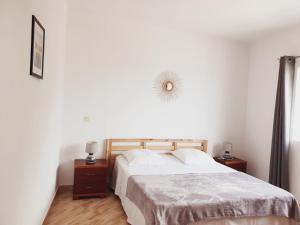 a white bedroom with a bed and two night stands at Residencia Solimar in Ponta do Sol