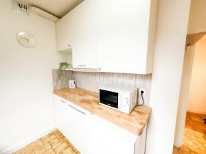 a kitchen with white cabinets and a microwave on a counter at Anh Dao 3 - Studio, centre ville, tiamconciergerie in Champs-Sur-Marne