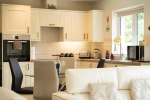 a kitchen with white cabinets and a white couch at Birch Hollow, Fort William with outdoor fire pit in Fort William