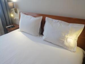a bed with white pillows and a wooden headboard at На 2 мин от плажа!Victoria- две спални делукс до Морската градина и центъра in Burgas